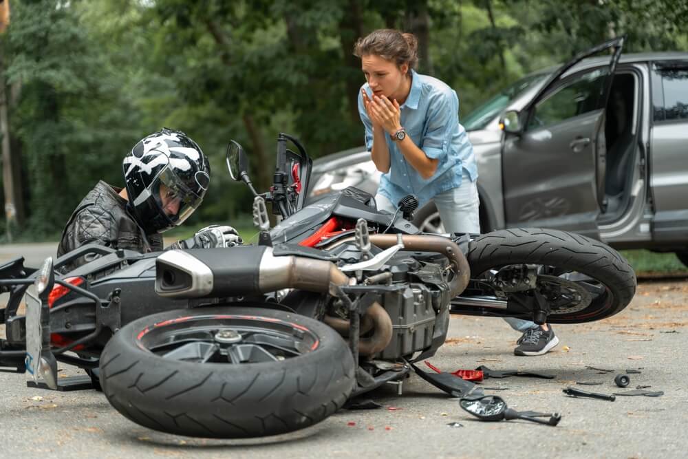 Collision between motorcycle and car on the road.